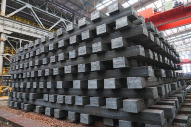 Yüksek sıcaklıkta yuvarlandıktan sonra çelik kirişler düzgünce bir araya toplanır ve soğuk koyu gri metal yüzey endüstriyel oksitlenme rengine sahiptir ki bu da büyük çelik fabrikasının karakteristik özelliğidir.