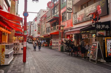 Kobe 'nin Çin Mahallesi, Nankinmachi' den Kobe, Hyogo, Japonya 'daki Çin pazarında dükkanlar ve gıda tezgahlarıyla çevrili turistler yolda yürüyorlar.