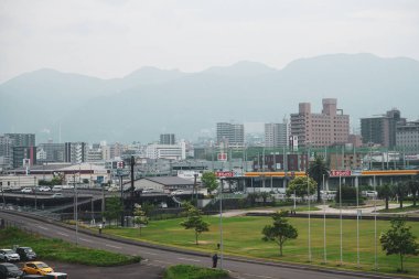 Beppu şehrinin silueti, şehir parkının yanındaki Beppu, Oita, Japonya 'daki liman ve sahil şeridinin yanındaki binalar ve yollar ile yükseliyor.