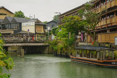 Arashiyama, Kyoto, Japonya 'daki Togetsukyo Köprüsü' nün yanındaki Katsura Nehri 'nde köprü ve tekneyle şehir manzarası