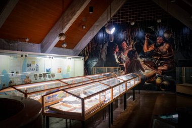 Ünlü Ryugado Mağara Müzesi 'nin içindeki vitrinlerde sergilenen sergilerde, duvarda Kami, Kochi, Japonya' daki Yayoi döneminden mağara sakinlerini gösteren bir duvar resmi bulunuyor.