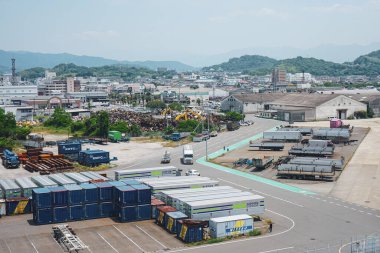 Matsuyama Limanı 'ndan görüldüğü üzere Matsuyama sanayi ve nakliye bölgesinden geçen araçlar, konteynırlar ve Japonya, Matsuyama, Ehime, Japonya' da bir çöplük.