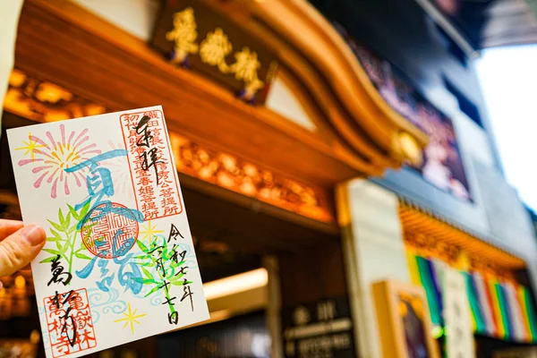 17 Haziran 2025 'te Japonya' nın Osu, Nagoya kentindeki Osu Alışveriş Sokağı 'ndaki Bansho-ji Tapınağı' ndan renkli bir Goshuin kağıt çarşafını tutan el.