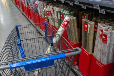 Bir alışverişçinin elinde bir rulo Noel hediyesi paketiyle bir Walmart süpermarketinin içinde Rio Rancho, New Mexico, ABD 'deki bir koridor boyunca alışveriş arabasını itmesi.