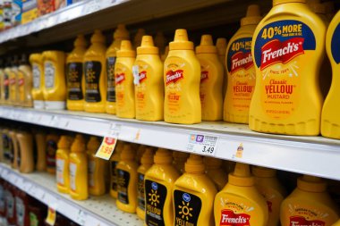 Bottles of yellow mustard, of several brands including French's, on a shelf inside a Smith's grocery store in Albuquerque, NM
