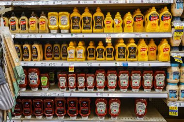 Variety of brands of ketchup and mustard on the shelf in the condiment aisle inside a Smith's grocery store in Albuquerque, NM, USA