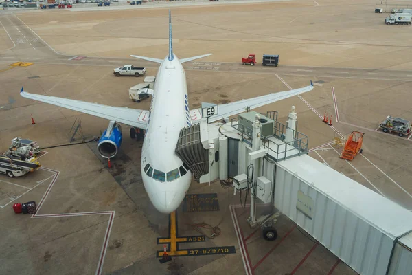 Teksas, ABD 'deki Dall Fort Worth Uluslararası Havalimanı' nda bağlı bir jet köprüsü olan bir uçağın tepesine bakan yüksek açılı görüntü.