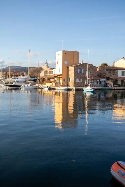 Güney Fransa 'da, Grimaud Limanı' ndaki marina ve liman binalarının manzarası. Gemiler güneşli havalarda, Fransız Rivierası 'ndaki Akdeniz atmosferinde durgun suya yansıyor..