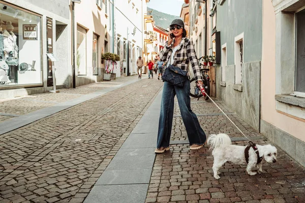 Ascona, Suisse2024-09-13. Sosyetik bir bayan Ascona sokaklarında köpeğini gezdirip telefonda konuşuyor. Fotoğraf: Jean-marc Vigneres