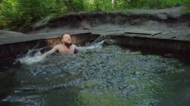 Adam suya su sıçratıyor. Tatil köyünde mutlu bir göl. Havuz temizleme spreyi