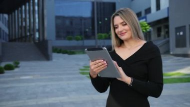 Şehirde tablet kullanan güzel bir genç kadın. İş kadınına yakın çekim.