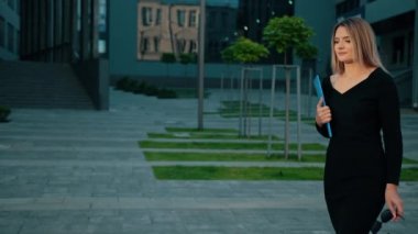 Dışarıda güneş gözlüklü bir kız var, mavi elleri klasör gibi. İş dünyası