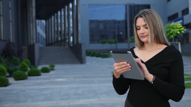 Бизнесвумен, использующая цифровые планшеты в финансовом районе, против небоскребов. — стоковое видео