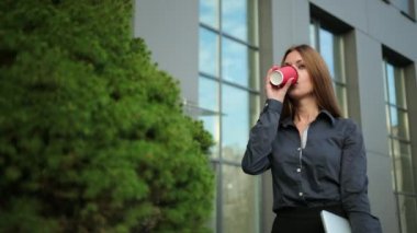 Genç iş kadını elinde bir kahve bilgisayarı içiyor. Güzel bayan, bir ofis.