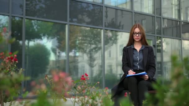 Zakenvrouw die documenten ondertekent in een rustige straat. Jonge vrouwelijke kantoormedewerker — Stockvideo