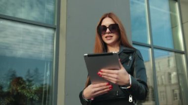 Gülümseyen genç kadın konuşuyor, tablet kullanıyor. Kahverengi saçlı kadın konuşuyor.