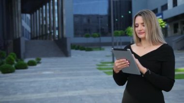 Şehirde tablet kullanan güzel bir genç kadın. İş kadınına yakın çekim.