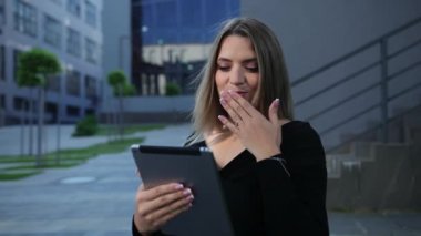 Şehirde tablet kullanan güzel bir genç kadın. İş kadınının elinde aygıtlar var.