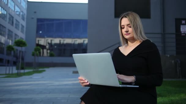 Vacker affärskvinna står utomhus modern byggnad. Damen som arbetar bärbar dator — Stockvideo