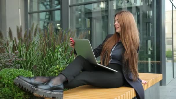 Γυναικεία πόδια σε ξύλινο πάγκο με laptop. Ελεύθερος επαγγελματίας, εξ αποστάσεως εργασία σε εξωτερικούς χώρους. — Αρχείο Βίντεο