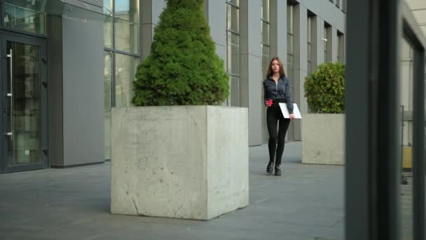 Una mujer joven sostiene un portátil. Exitosa mujer de negocios con computadora. Ciudad — Vídeo de stock