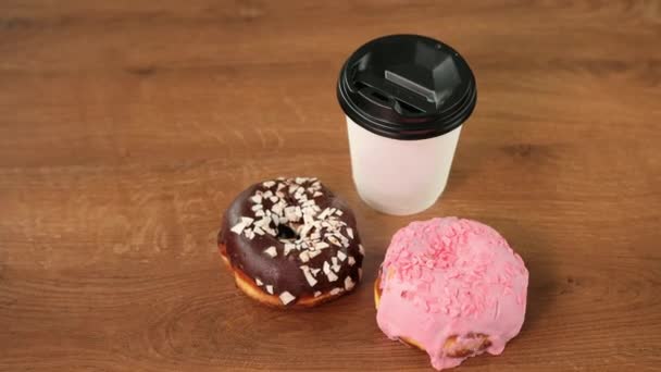 Frische handwerkliche Donuts, Kaffee zum Mitnehmen, Holztischhintergrund, leckerer Donut — Stockvideo