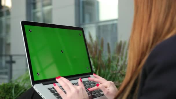 Женские руки работают на зеленом экране ноутбука. Женщина с помощью хроматического ключа ноутбука — стоковое видео