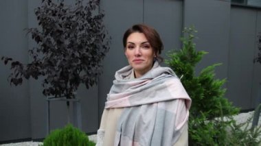 Kameraya bakıp başını gülümseyerek sallayan genç bir kadının yakın plan portresi.