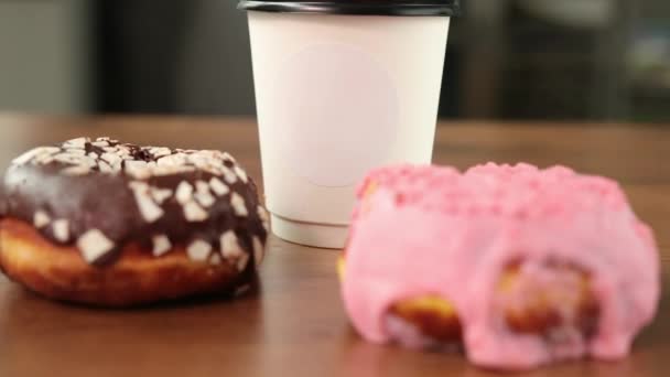 新鲜的手工艺者甜甜圈，带走咖啡，木制餐桌背景，美味的甜甜圈 — 图库视频影像