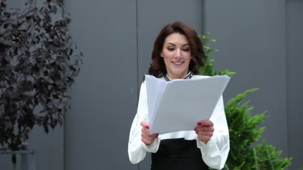 Woman skilled CEO reading information paper documents standing outside business — Stock Video