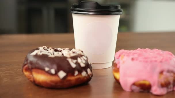 Frische handwerkliche Donuts, Kaffee zum Mitnehmen, Holztischhintergrund, leckerer Donut — Stockvideo