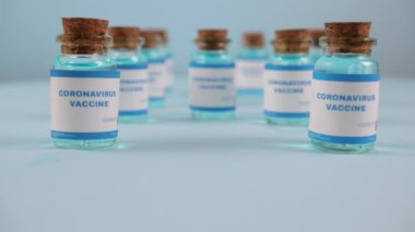 Şırınga iğnesi, bir damla sıvı, mavi arka planda bulanık pfizer şirketi..