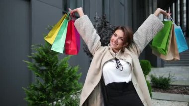 Elinde renkli alışveriş torbaları tutan bir kadın. Güzel milenyum modeli bayan.