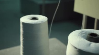 Tekstil iplikleri endüstrisi. Makinede beyaz iplik duruyor. Yakın plan.