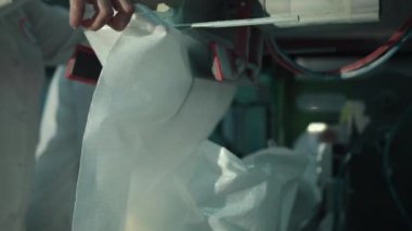 Bir kadın işçi şeker pancarı bitkisinin konveyör bandında makine kullanarak şeker paketler.