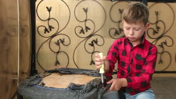 Boy repara la silla con un destornillador desenrosca aprieta el tornillo, perno. Maestro. — Vídeos de Stock