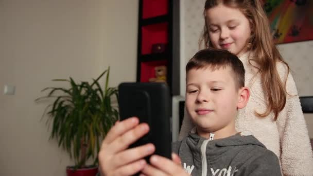 Boy holds a smartphone girl throws her hair over his head. Attractive — Stock Video