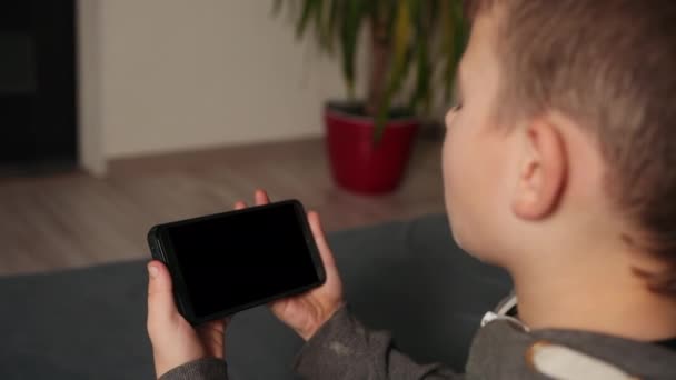 Ung pojke med videochatt på smartphone hemma, närbild. Utformningsutrymme. — Stockvideo