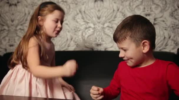 Маленький хлопчик і дівчинка грають у рок-паперові ножиці. Щасливі діти, діти грають у гру — стокове відео