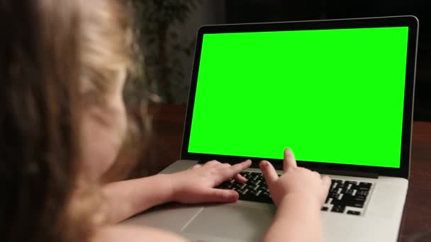 Di atas bahu gadis kecil menggunakan laptop dengan layar hijau mock-up pada layar display. — Stok Video