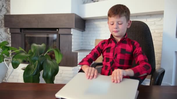 Young caucasian boy study home with internet laptop computer sitting on chair — Stock Video