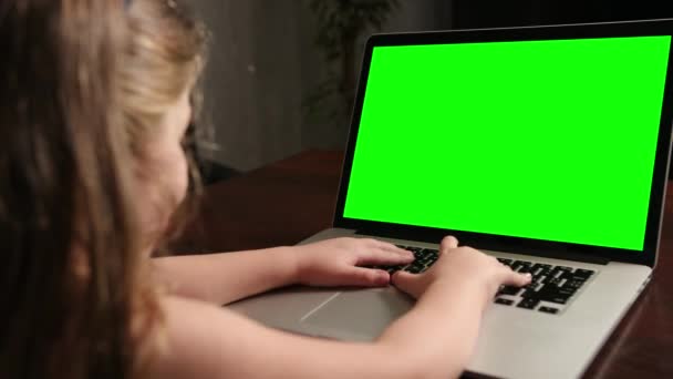 Přes rameno holčička použít notebook se zelenou obrazovkou maketa-up na displeji. — Stock video