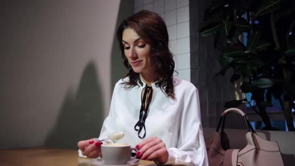 Junge Frau trinkt Latte im sommerlichen Morgencafé. Brünette Dame — Stockvideo