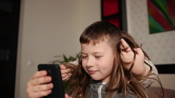 Boy holds a smartphone girl throws her hair over his head. Attractive — Stock Video
