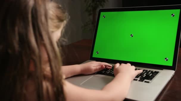 Vue de la fille arrière assise à la table et tapant sur la clé chromatique verte ordinateur portable — Video