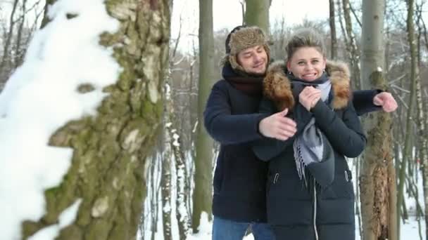 Mężczyzna przytulający kobietę z bliska w zaśnieżonym lesie. Atmosferyczny moment zmysłowy. — Wideo stockowe