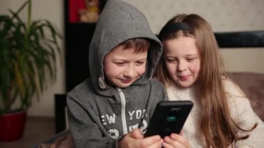 Akıllı telefon kullanan komik çocuklar video izleyip gülüyorlar, arkadaşlık ediyorlar, çocukluk yapıyorlar.