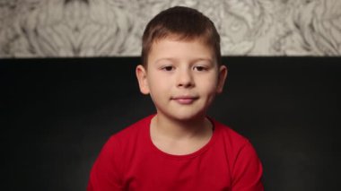 Kameraya bakıp gülümseyen bir çocuğun portresi. Sosyal uzaklık ve izolasyon