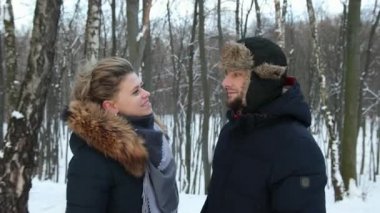 Mutlu çift, kadın karla kaplı kış ormanında donmuş adama eşarp takıyor.