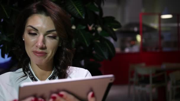 Молода і красива жінка розмовляє через відео посилання на планшет за столом у кафе . — стокове відео